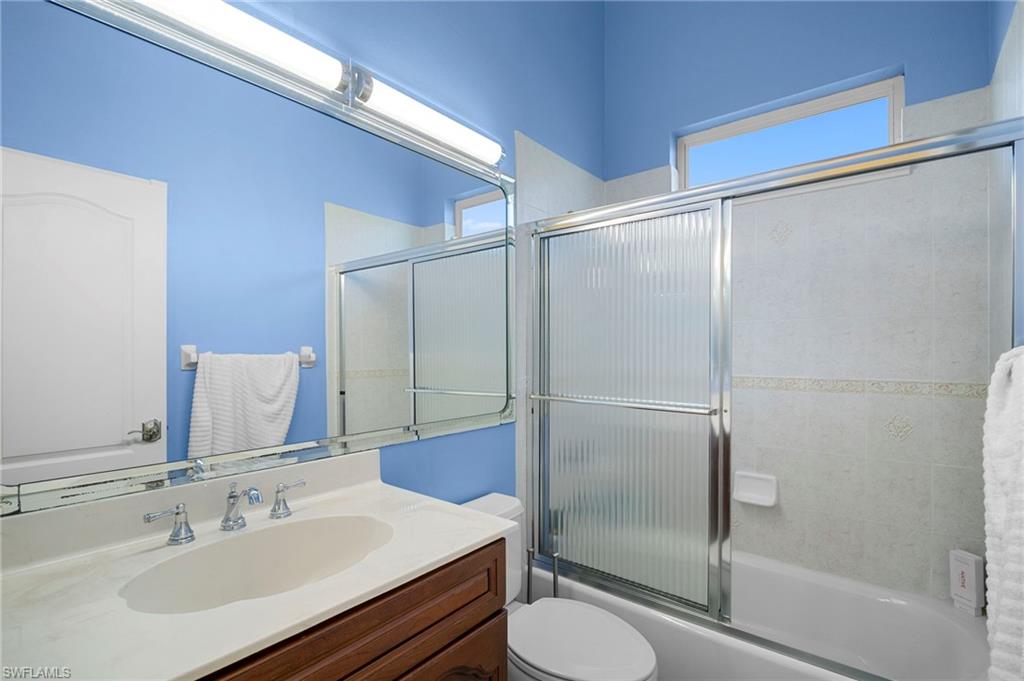Bathroom featuring vanity, plenty of natural light, and shower / bath combination with glass door
