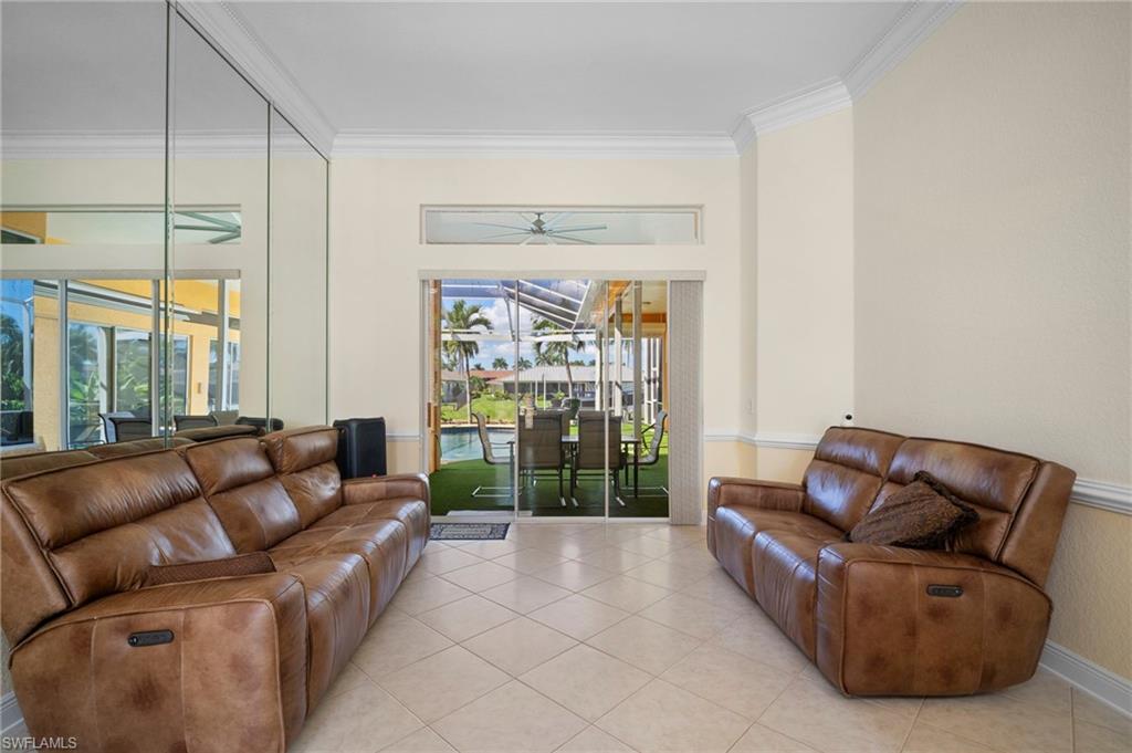 Living area featuring a sunroom, tile patterned flooring, and crown molding