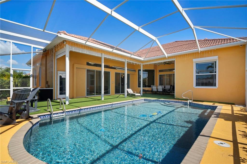 Back of property featuring a sunroom, ceiling fan, glass enclosure, an outdoor pool, and a patio area