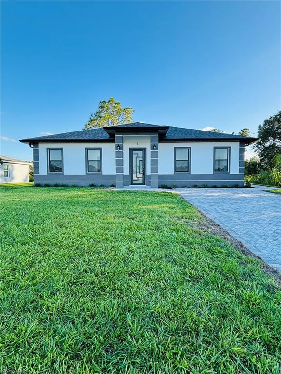 Prairie-style home with a front lawn, stucco siding, and roof with shingles