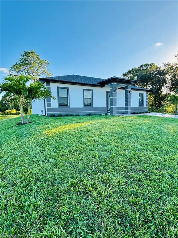 Ranch-style home with a front lawn and stucco siding