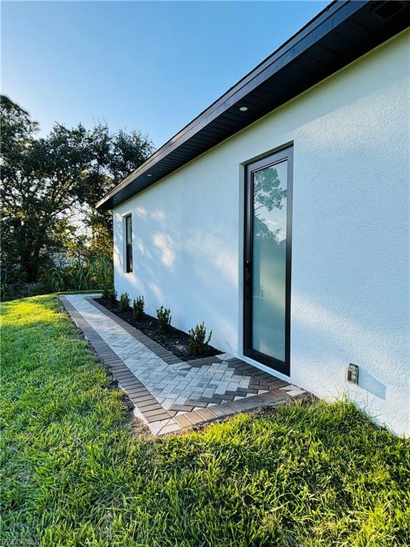View of side of property with stucco siding, a lawn, and crawl space