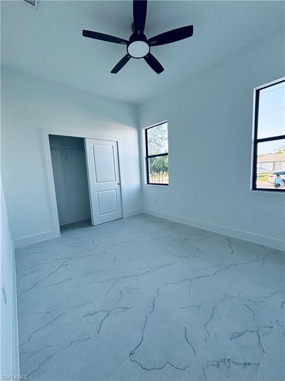 Unfurnished bedroom featuring ceiling fan, light marble finish floors, and a closet