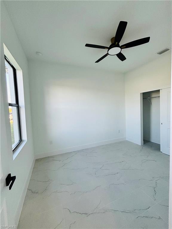 Unfurnished bedroom featuring light marble finish floors, a closet, and ceiling fan