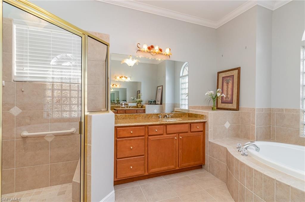 Bathroom featuring ornamental molding, vanity, light tile patterned floors, a stall shower, and a bath