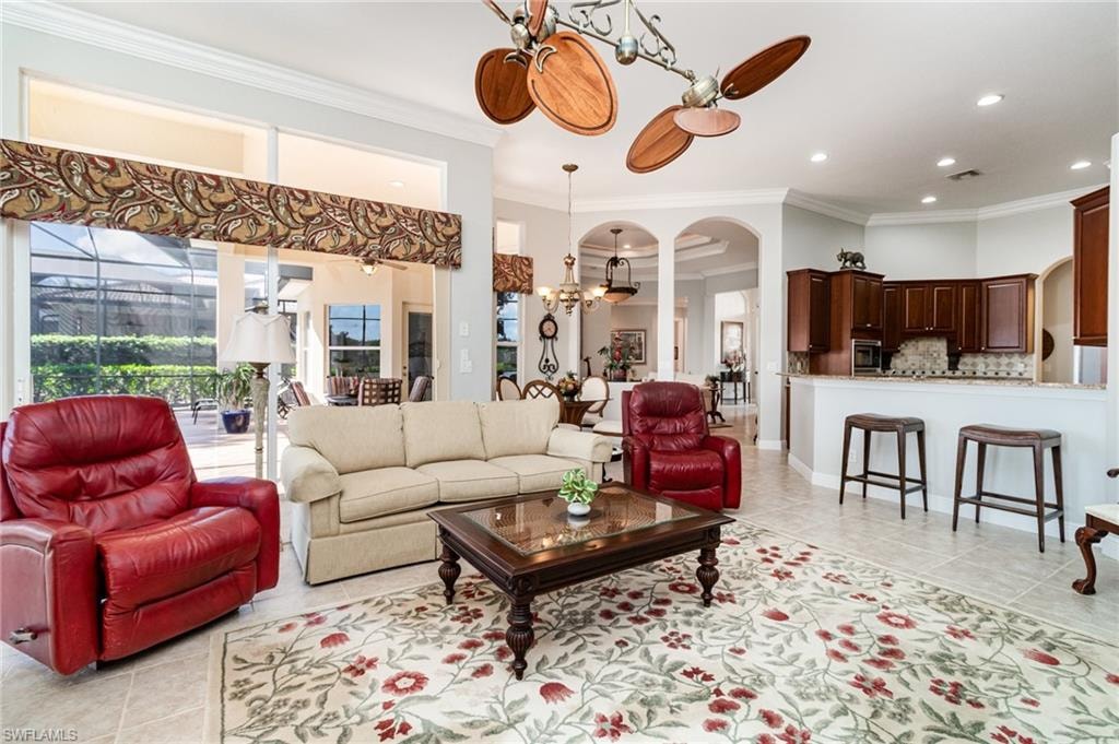 Living area featuring light tile patterned flooring, crown molding, recessed lighting, and arched walkways