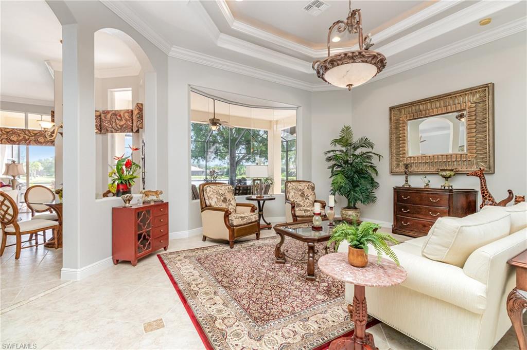 Sitting room featuring a raised ceiling, ornamental molding, arched walkways, and light tile patterned floors