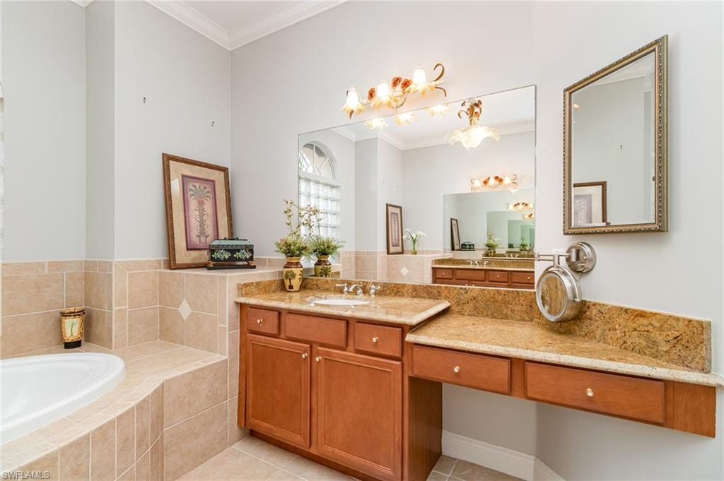 Full bath featuring crown molding, a bath, light tile patterned floors, and vanity