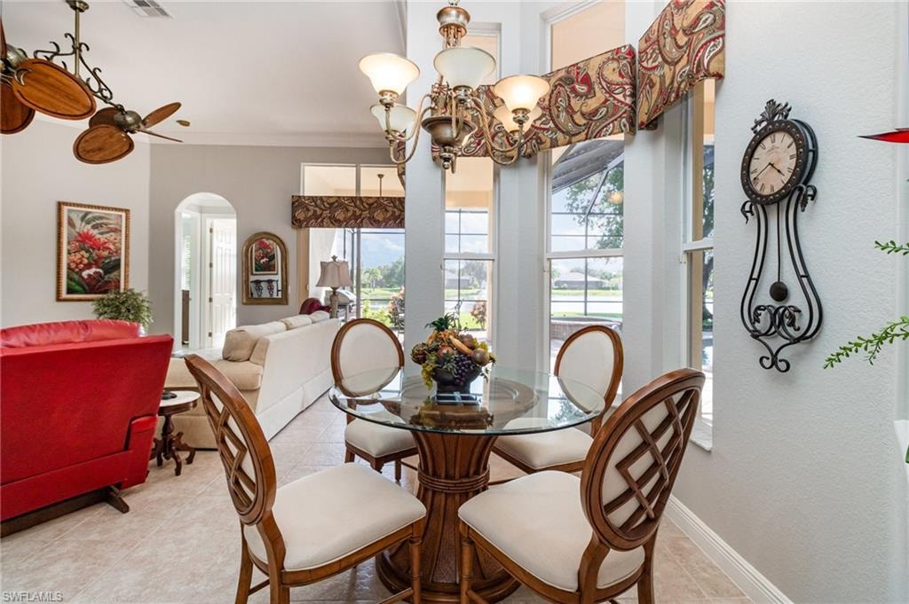 Dining space featuring arched walkways, a chandelier, crown molding, and light tile patterned flooring