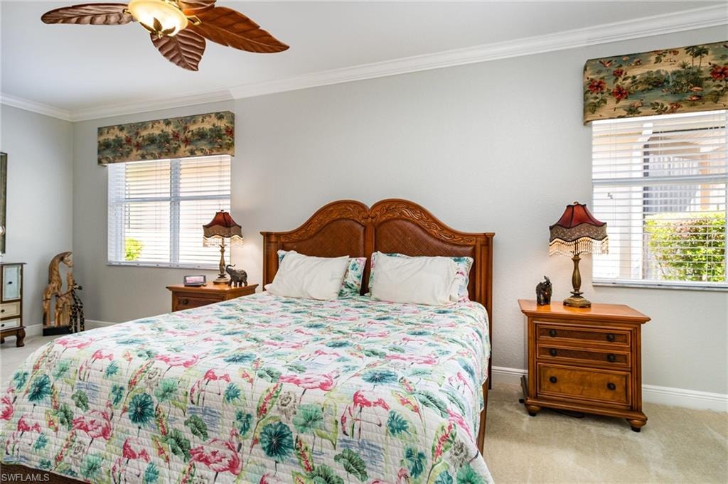 Bedroom featuring ornamental molding, light colored carpet, a ceiling fan, and multiple windows
