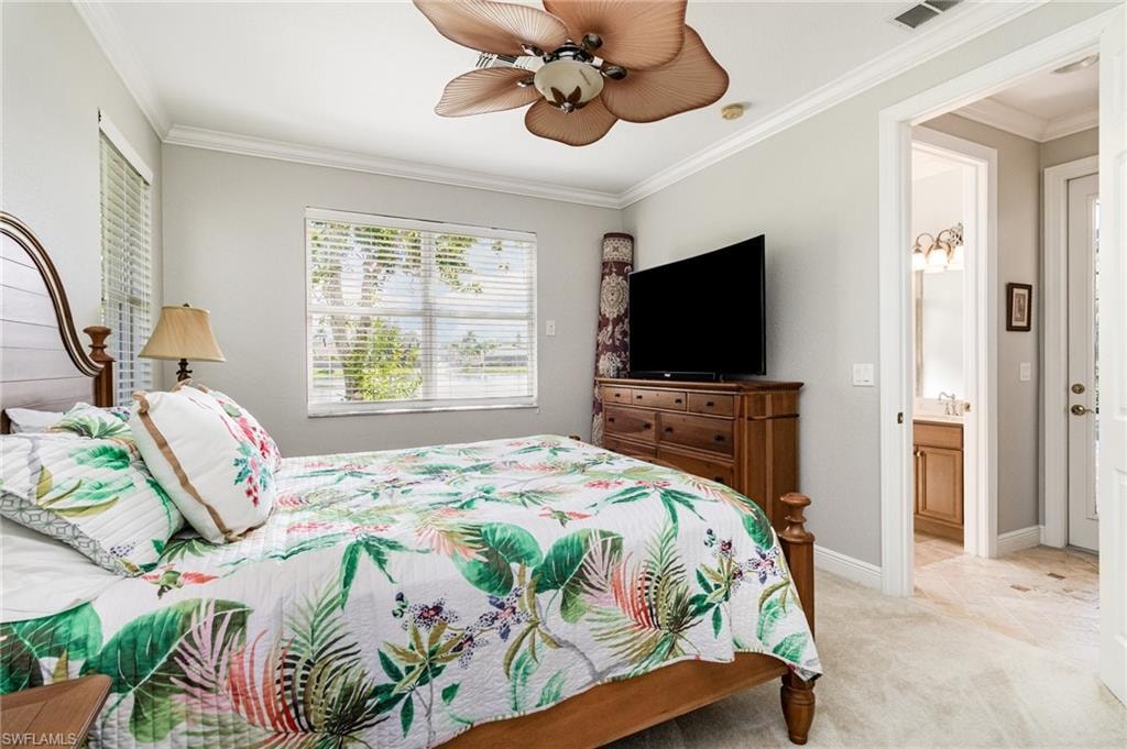 Bedroom featuring ornamental molding, light colored carpet, ceiling fan, and ensuite bath