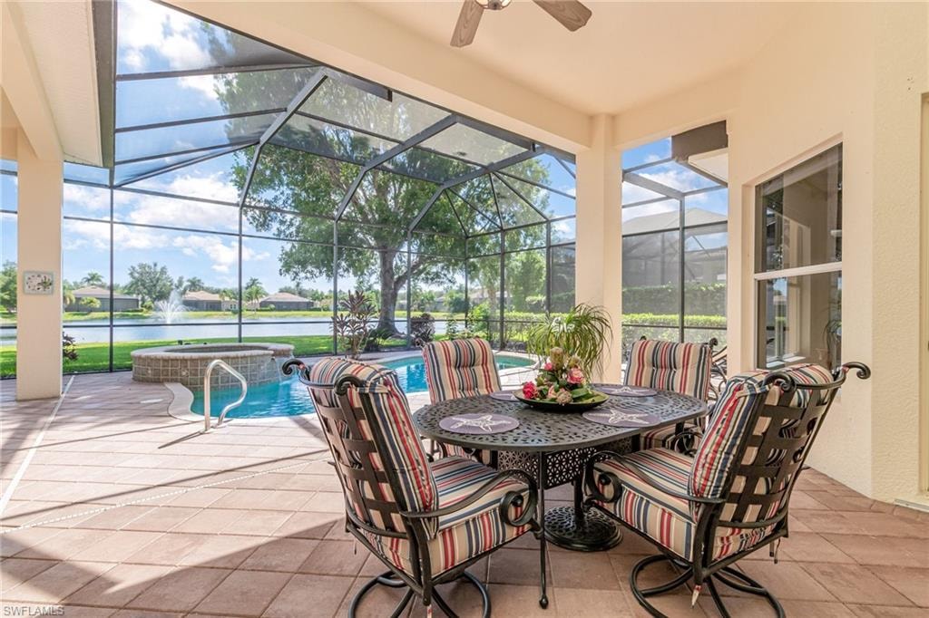 Sunroom / solarium with a water view, a patio, ceiling fan, and a hot tub