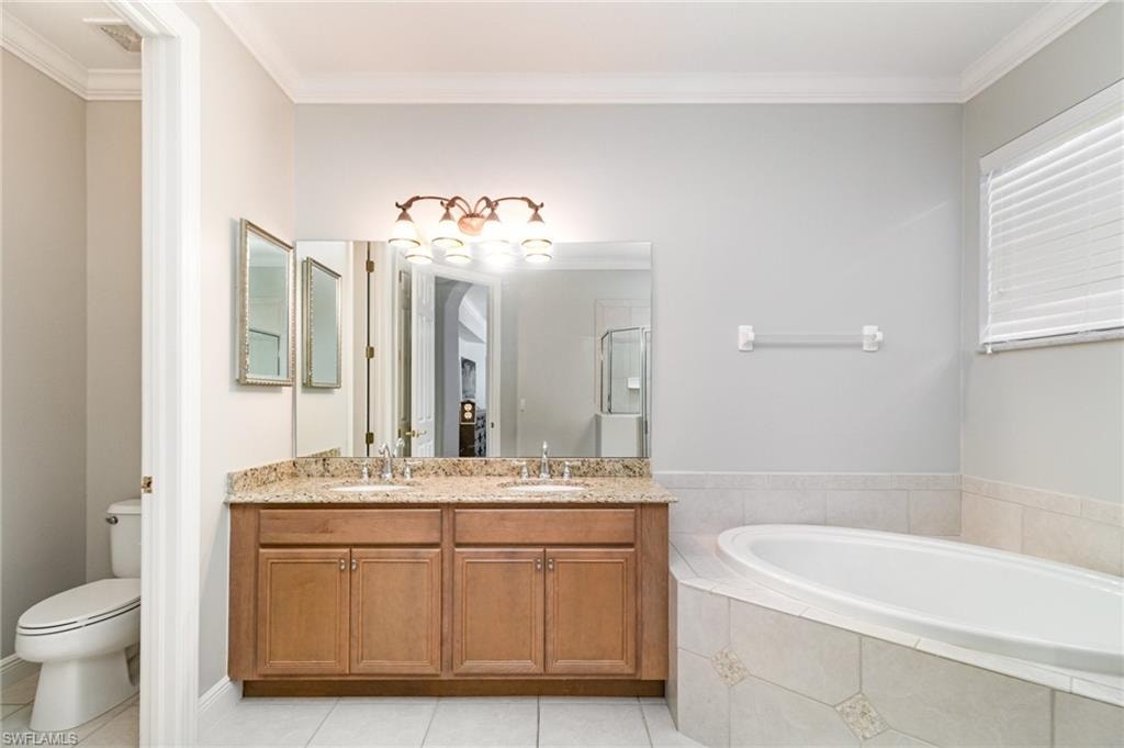Full bath with crown molding, a garden tub, light tile patterned flooring, double vanity, and a shower stall