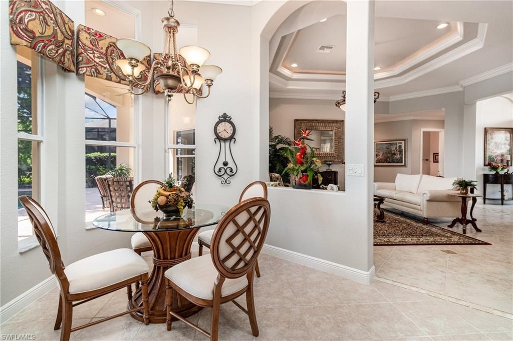 Tiled dining area featuring a tray ceiling, crown molding, a chandelier, and recessed lighting
