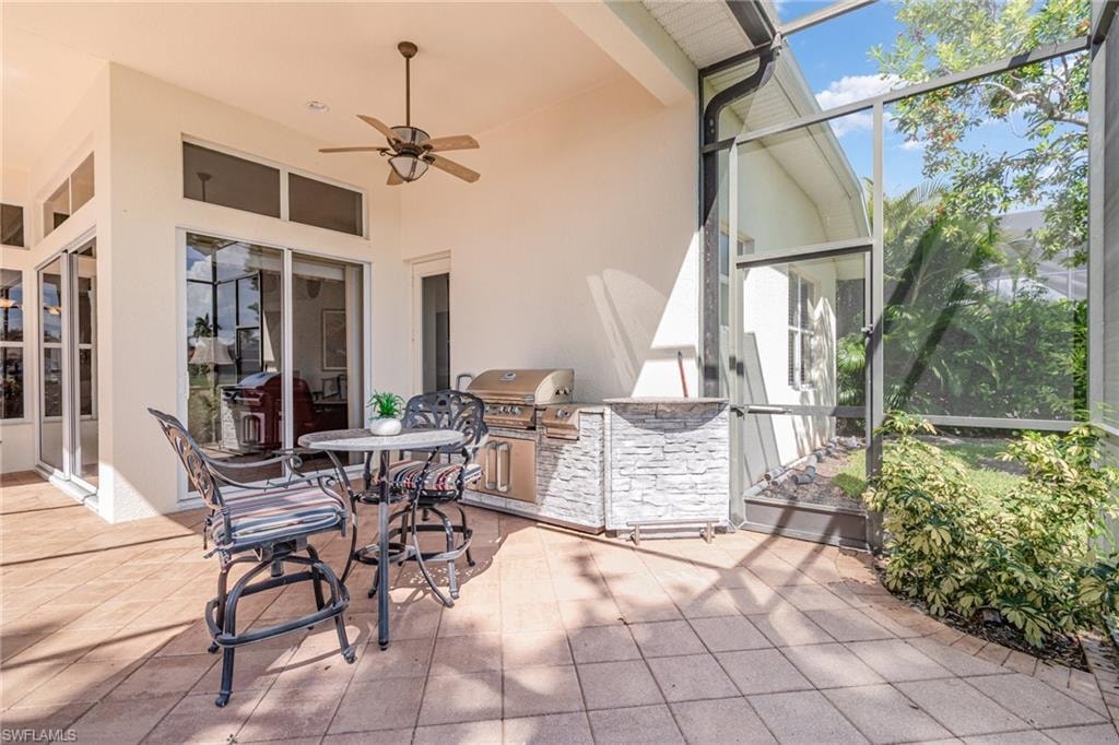 View of patio / terrace featuring ceiling fan, a lanai, an outdoor kitchen, and a sunroom