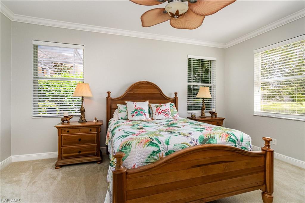 Bedroom featuring ornamental molding, light colored carpet, multiple windows, and a ceiling fan