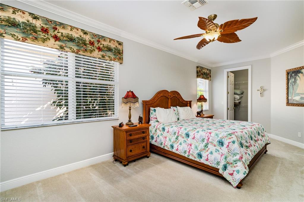 Bedroom with a spacious closet, carpet, crown molding, and a ceiling fan