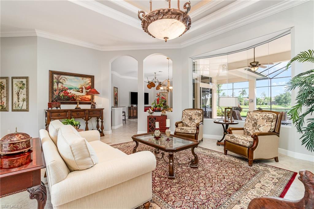 Sitting room with crown molding, light tile patterned floors, arched walkways, a ceiling fan, and a chandelier