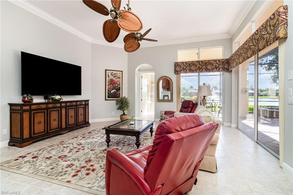 Living room featuring ornamental molding, arched walkways, a ceiling fan, and light tile patterned floors
