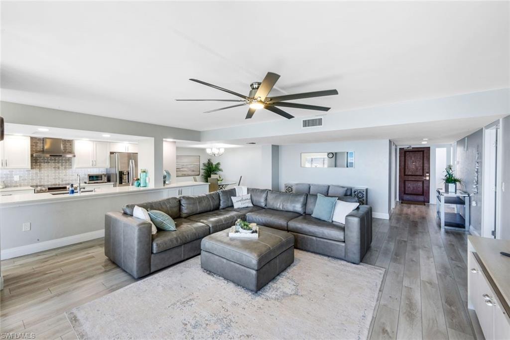 Living room featuring light wood-style flooring, ceiling fan, recessed lighting, and a chandelier