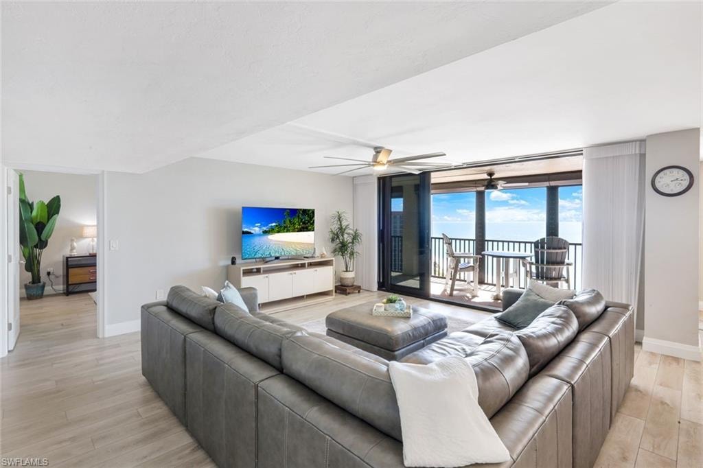 Living room featuring ceiling fan, light wood-type flooring, and floor to ceiling windows
