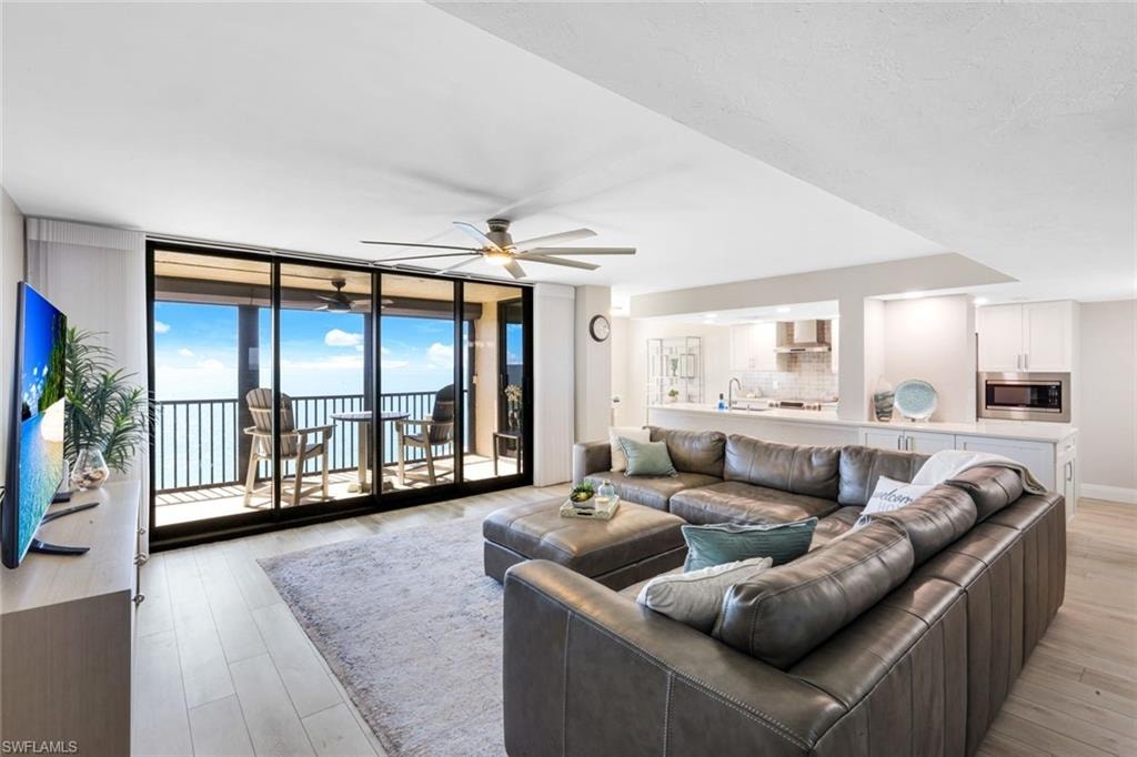 Living area featuring expansive windows, light wood-type flooring, and ceiling fan
