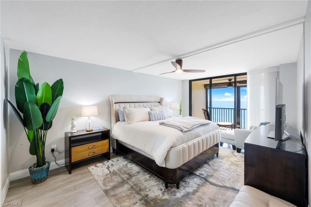 Bedroom featuring wood finished floors, a ceiling fan, access to exterior, and floor to ceiling windows