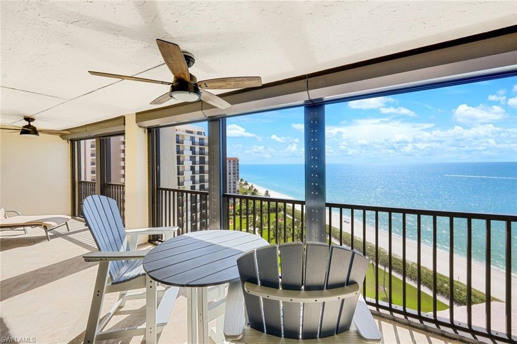 Sunroom with view of water and beach, a wall of windows, and a textured ceiling