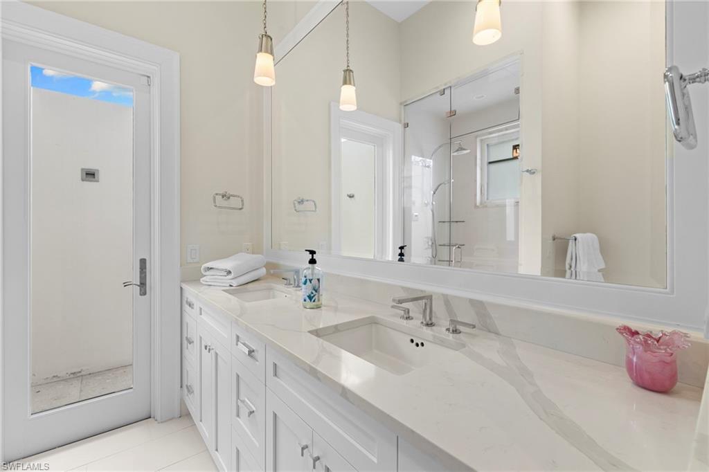 Bathroom featuring double vanity, a shower stall, and light tile patterned floors