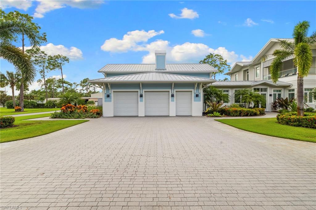 View of home's exterior featuring a metal roof, decorative driveway, a standing seam roof, an attached garage, and a lawn