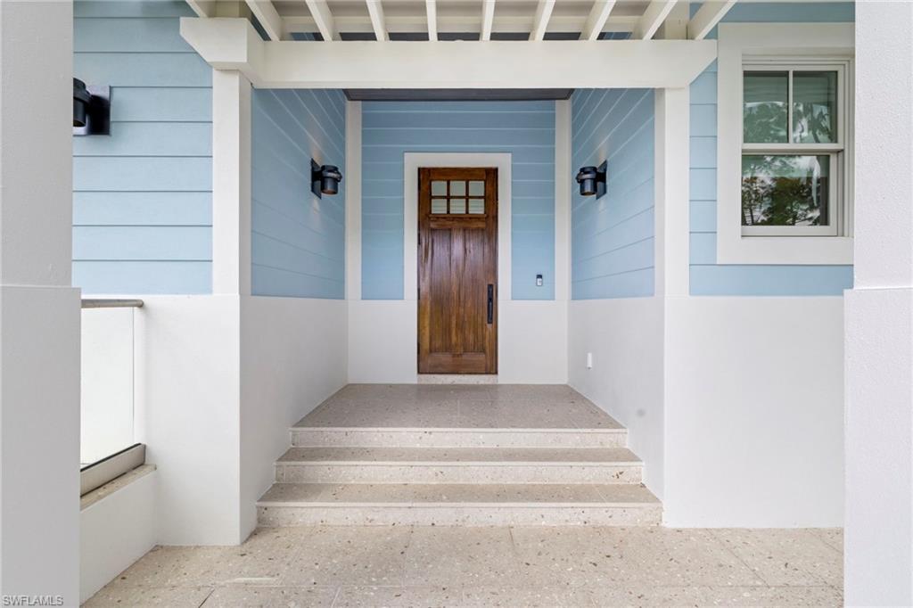 Doorway to property featuring covered porch and stucco siding