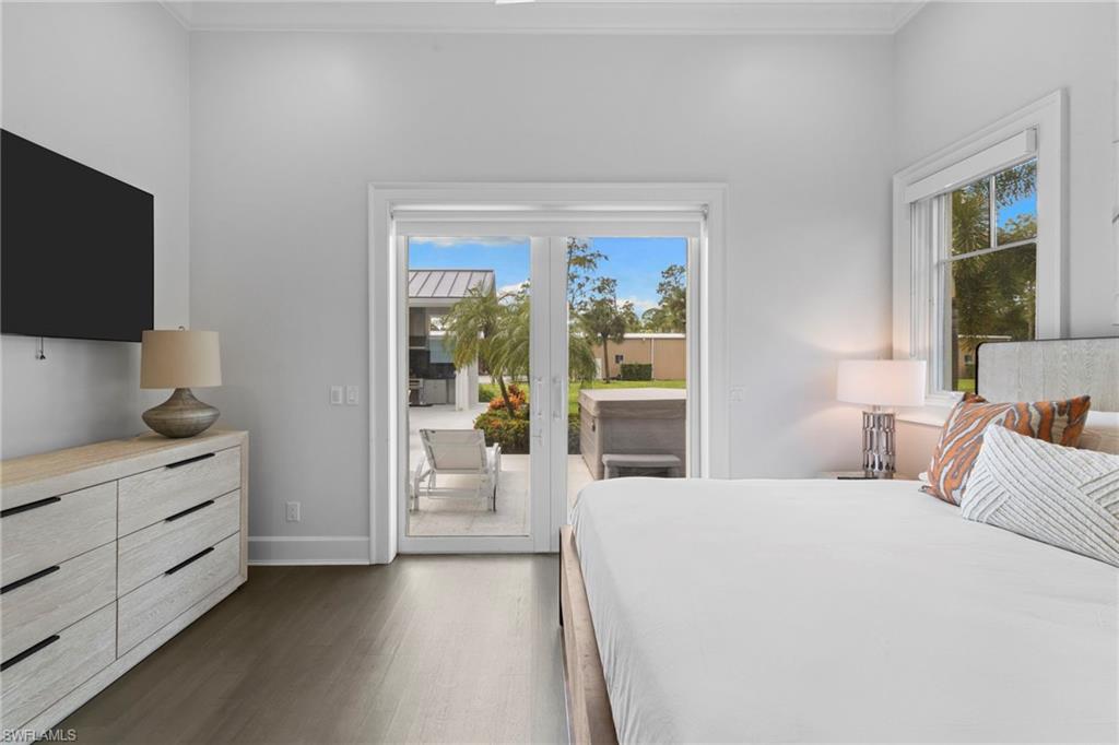Bedroom with multiple windows, dark wood finished floors, access to exterior, french doors, and crown molding
