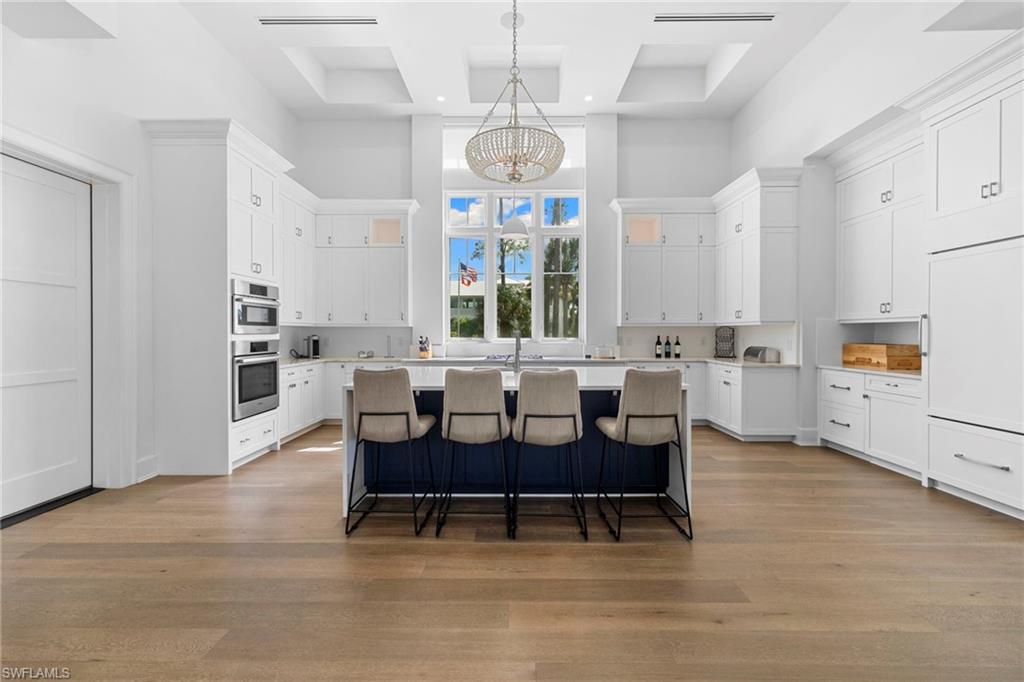 Kitchen with a chandelier, a breakfast bar, a kitchen island with sink, white cabinetry, and pendant lighting