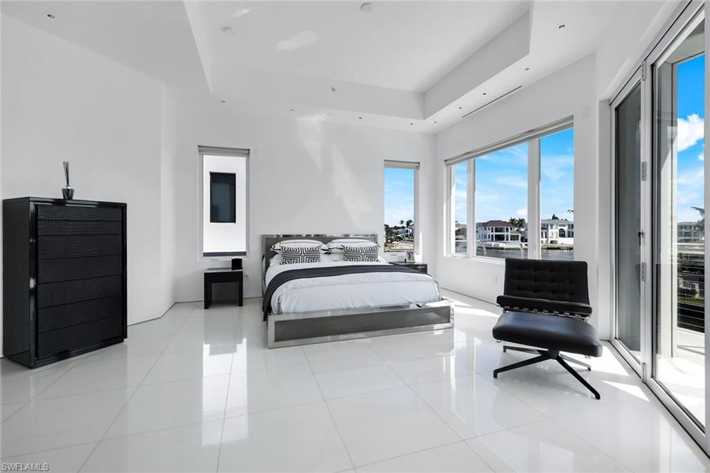 Bedroom with access to exterior, a raised ceiling, and light tile patterned floors