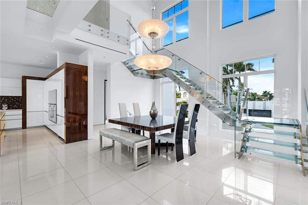 Elegant dining room with glass and stainless-steel staircase and marble flooring.
