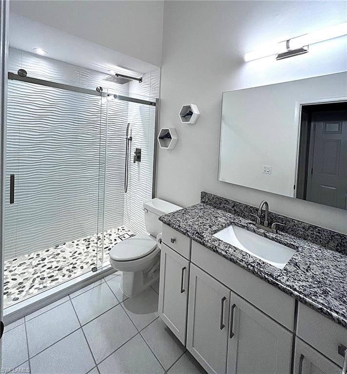 Full bathroom with vanity, light tile patterned flooring, and a stall shower