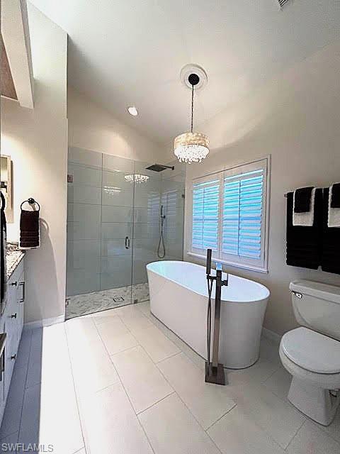 Full bathroom with a soaking tub, vanity, a stall shower, vaulted ceiling, and light tile patterned floors