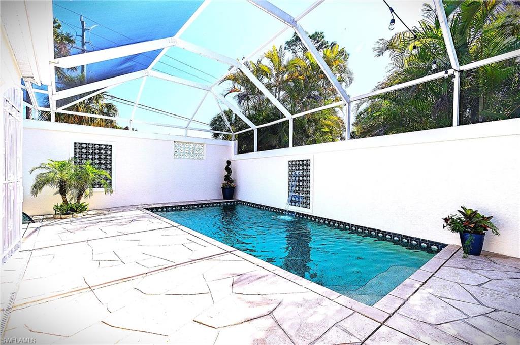 Swimming pool featuring a patio area, glass enclosure, and a sunroom