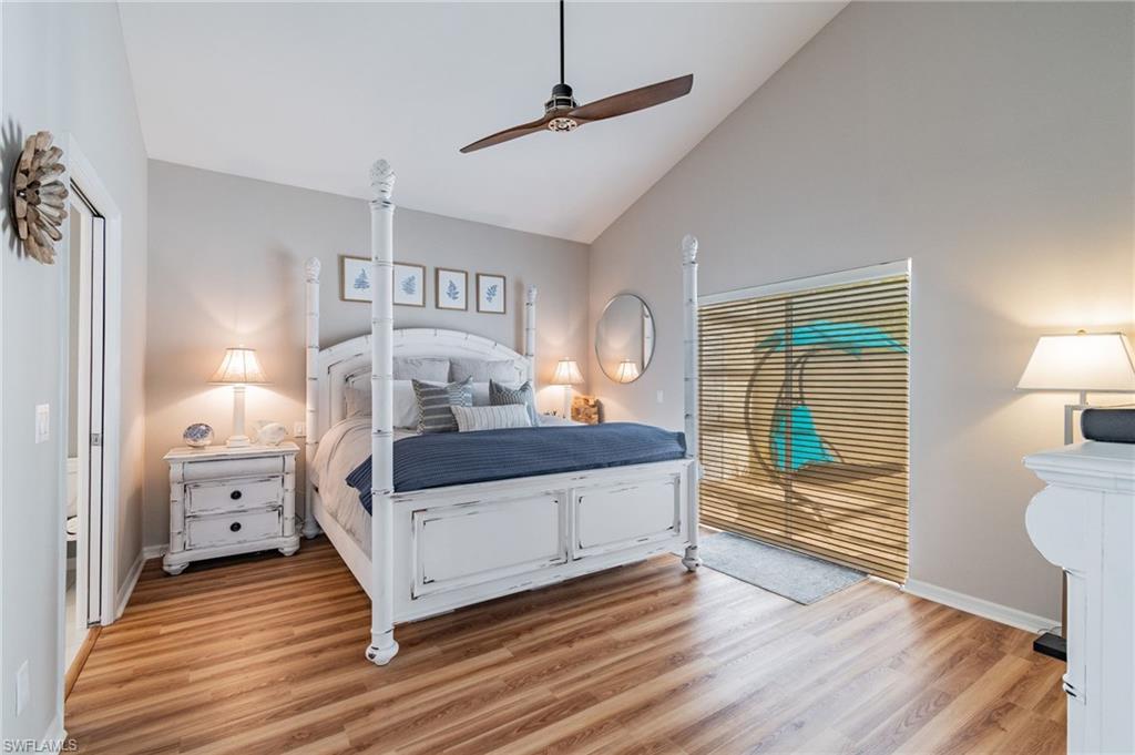 Bedroom with light wood-style floors, high vaulted ceiling, and a ceiling fan