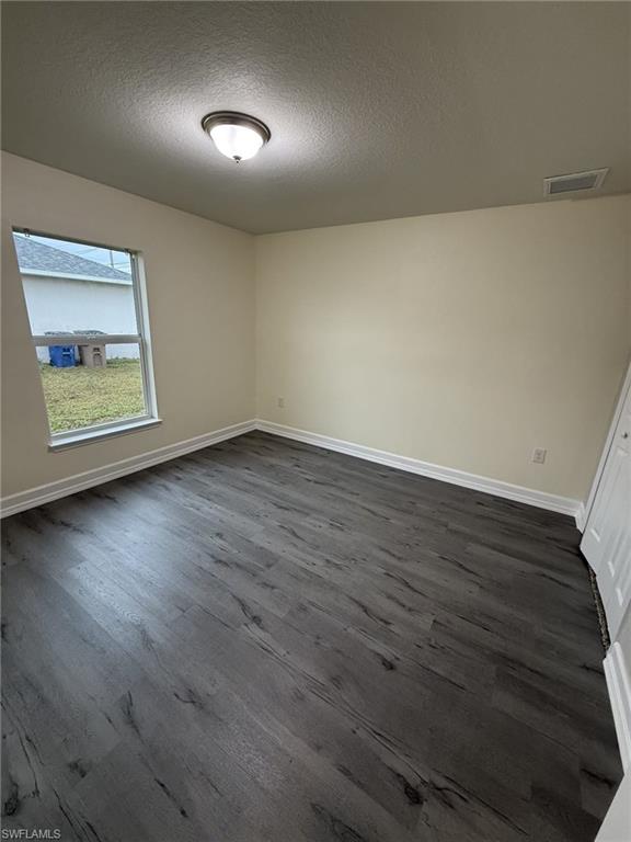 Spare room featuring dark wood finished floors and a textured ceiling