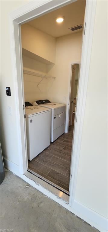 Laundry area with wood finish floors, washer and dryer, and recessed lighting