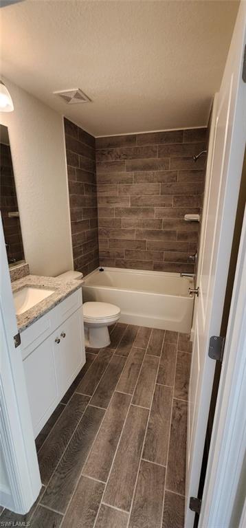 Bathroom featuring vanity, wood finish floors, shower / tub combination, and a textured ceiling