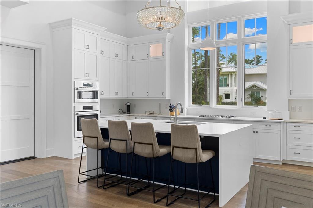 Kitchen with white cabinetry, a kitchen island with sink, a breakfast bar area, and a towering ceiling