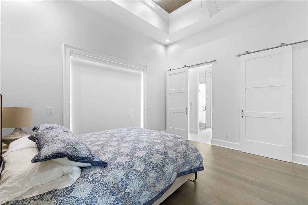 Bedroom with wood finished floors, connected bathroom, and a barn door