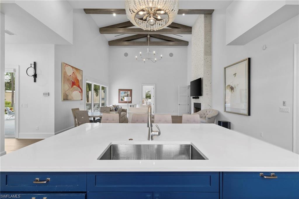 Kitchen with blue cabinets, high vaulted ceiling, beam ceiling, a center island with sink, and open floor plan