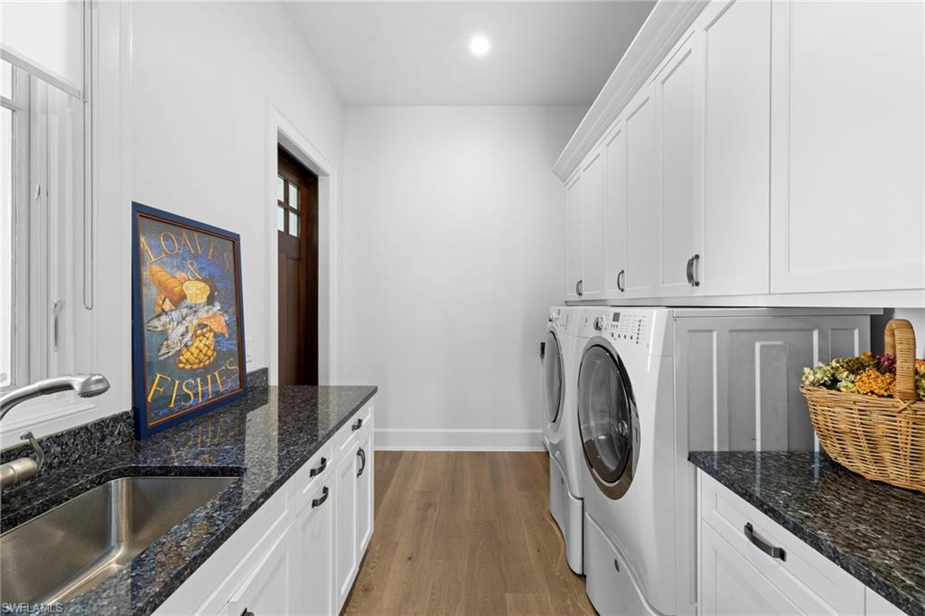 Laundry area featuring dark wood-type flooring, cabinet space, and independent washer and dryer