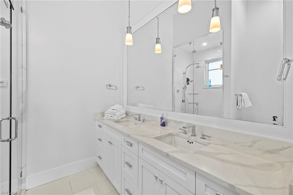 Bathroom featuring double vanity, light tile patterned floors, and a stall shower