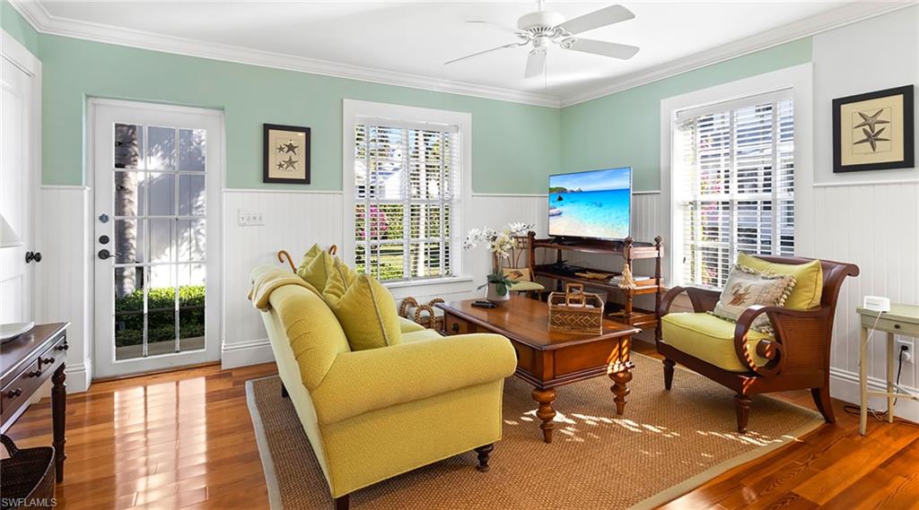 Sitting room with ornamental molding, wood finished floors, a ceiling fan, and wainscoting