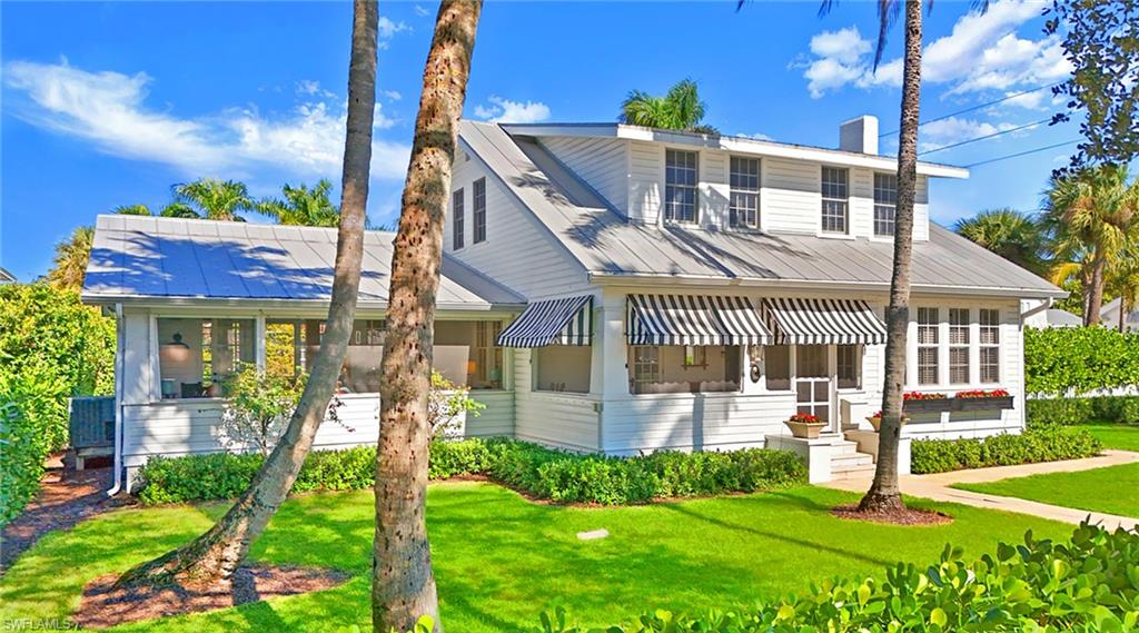View of front of property featuring a front lawn, a chimney, a sunroom, and a metal roof