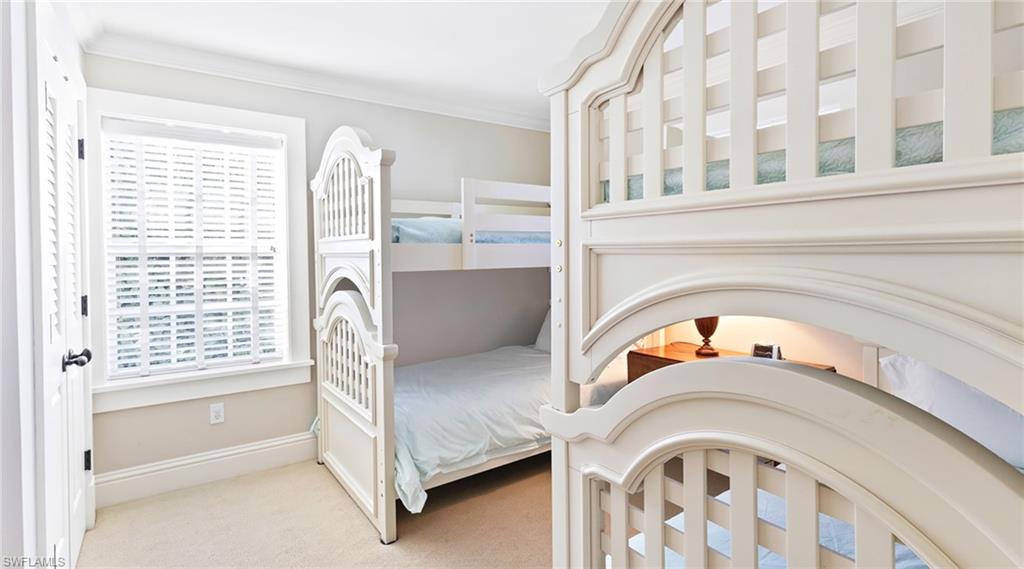 Carpeted bedroom featuring crown molding and baseboards